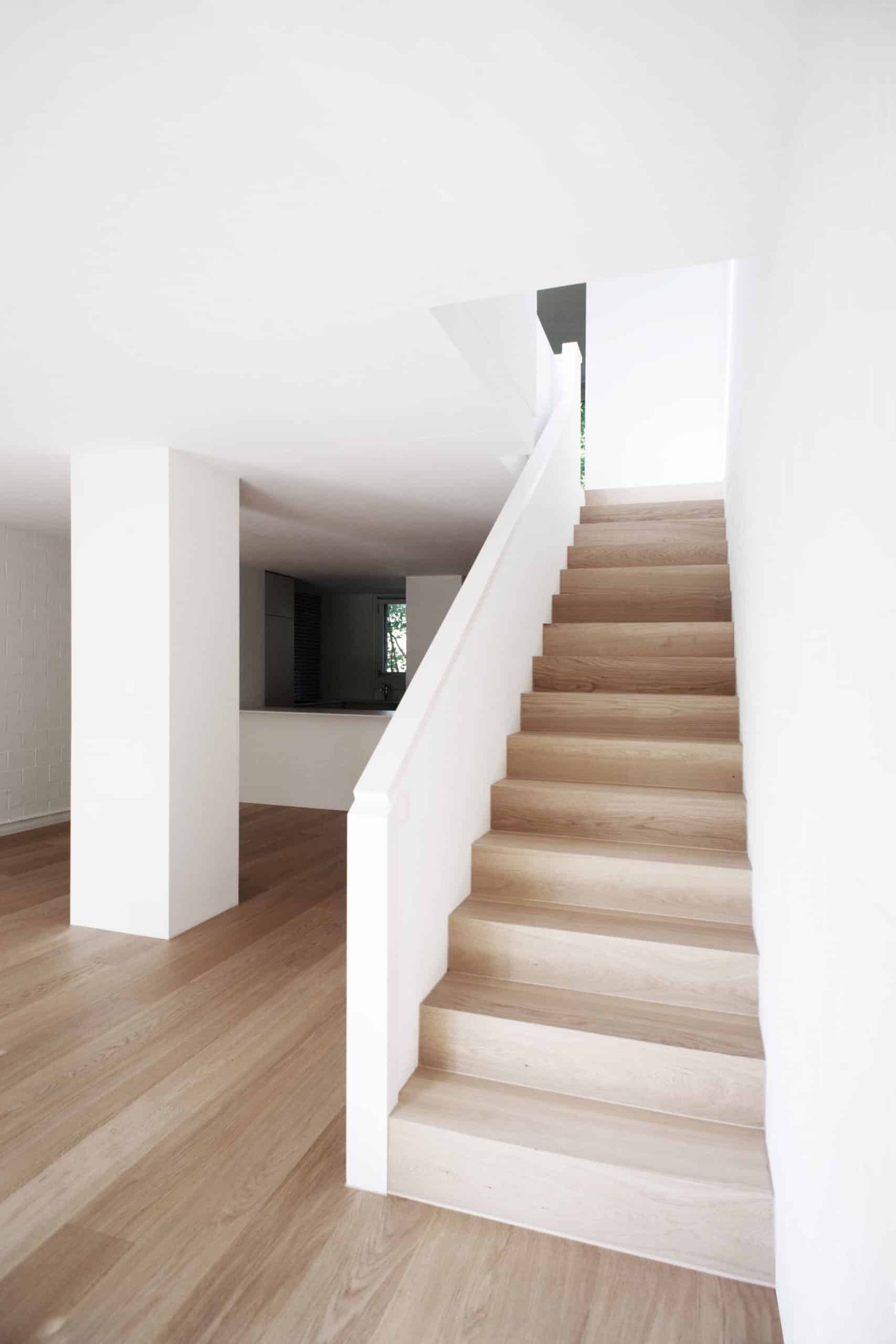 Moderne Treppe aus hellem Holz in einem Innenraum mit weißen Wänden. KGRUPPE Architekten Basel