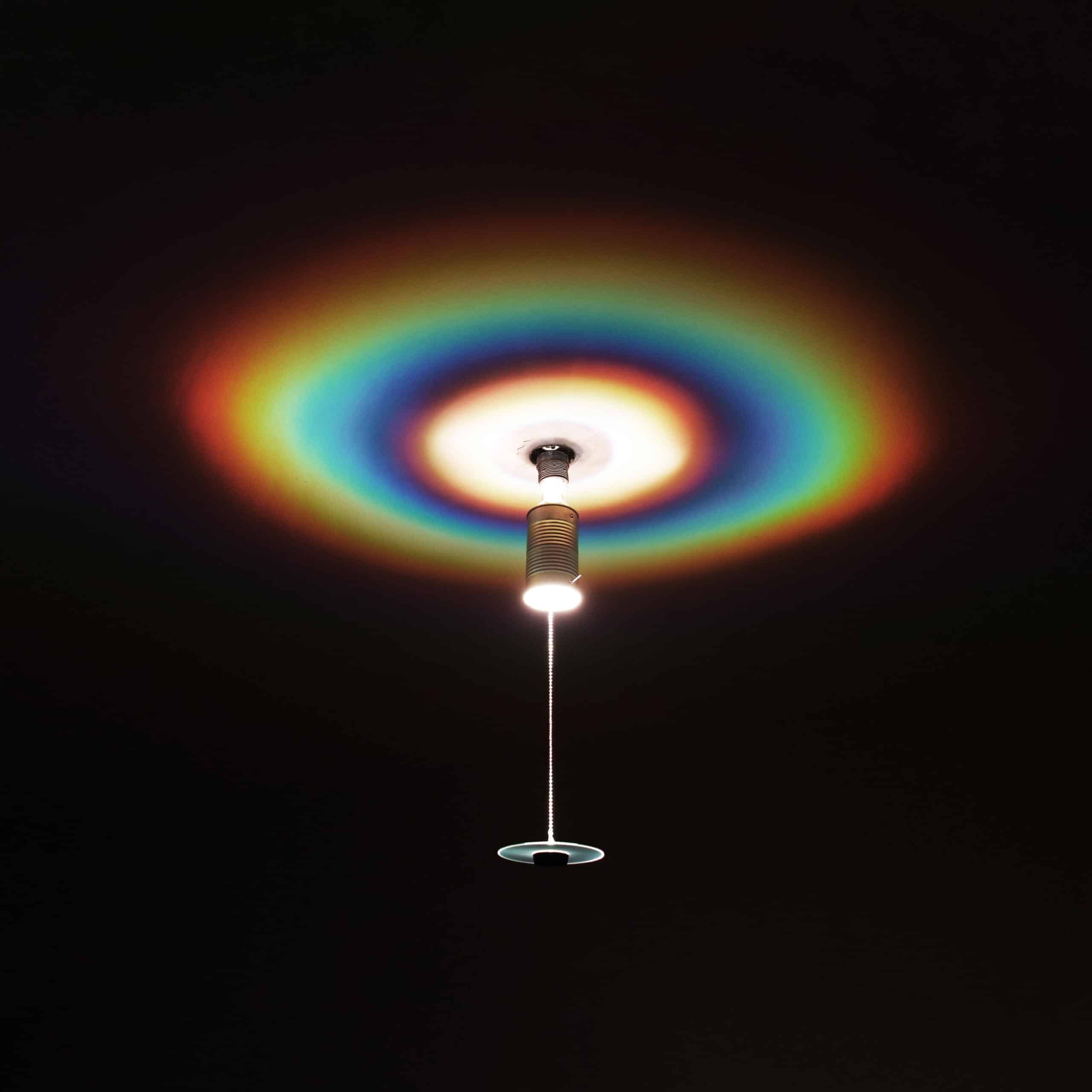 Deckenlampe mit Regenbogeneffekt auf dunklem Hintergrund.