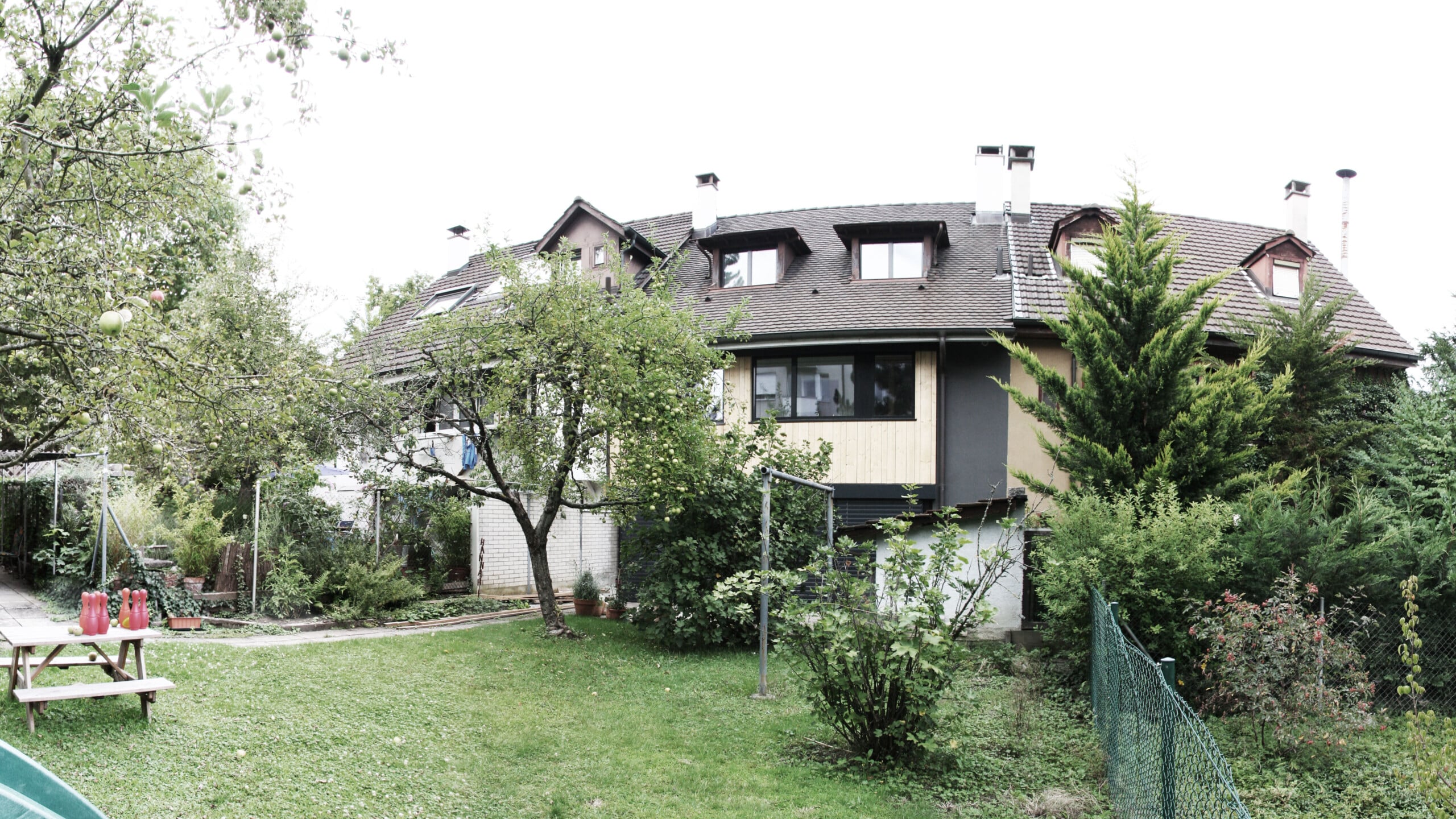 Umbau von KGRUPPE Architekten Basel - Wohnhaus mit Garten und Obstbäumen im Vordergrund.