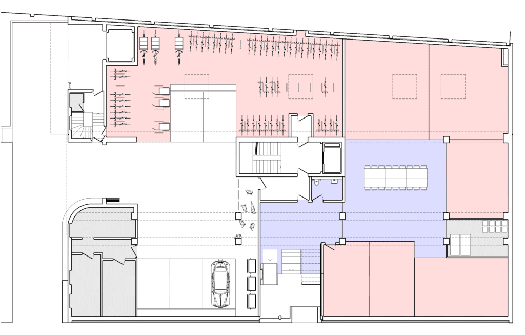 Umbau, Umnutzung und Wettbewerb von KGRUPPE Architekten Basel - Grundriss eines Gebäudes mit farblich markierten Bereichen in Rot und Blau. Links oben befinden sich Arbeitsplätze. Rechts daneben ist ein grosser, offener Raum mit Tischen und Stühlen. Unten links eine Garage mit Fahrzeug.