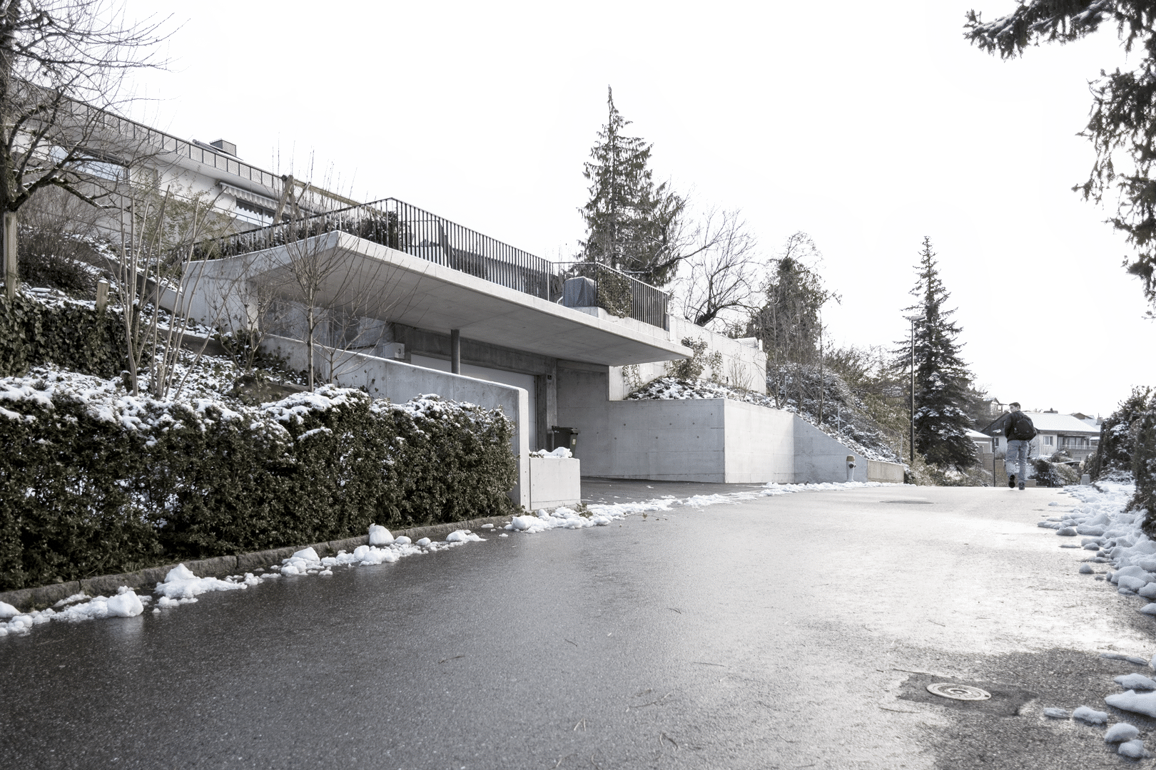 Umbau und Anbau eines Einfamilienhauses mit Betonpool durch das Architekturbüro KGRUPPE Architekten Basel. Das Foto zeigt die moderne Wohnhausfassade im Winter mit Schnee.